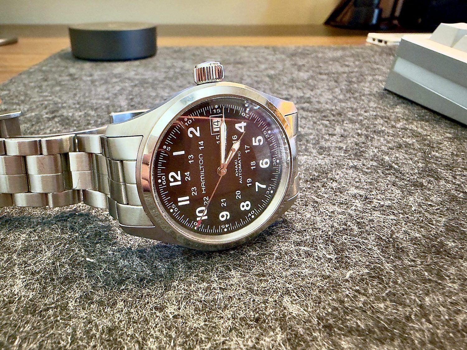 The Khaki Field dial photographed at an angle, showing reflection across the sapphire crystal and the oversized crown